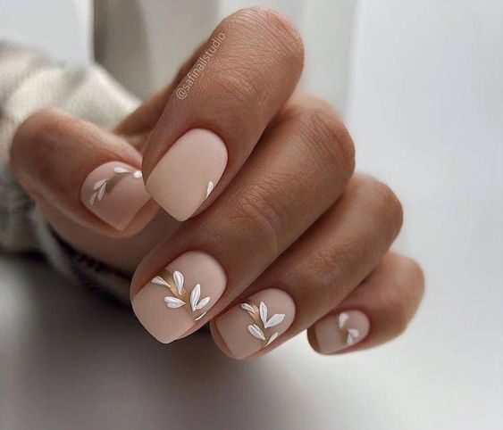 Vernis à ongles de couleur neutre avec des feuilles au fini mat nail art sur ongles carrés courts et effilés