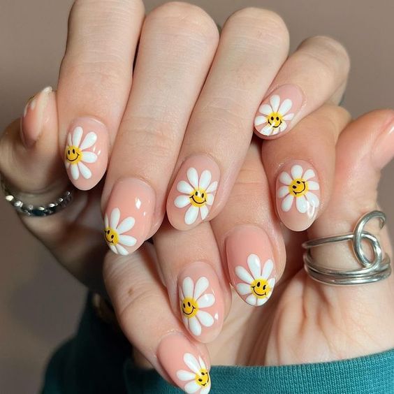 Ongles courts en acrylique en forme d’amande avec des fleurs blanches et des visages souriants nail art