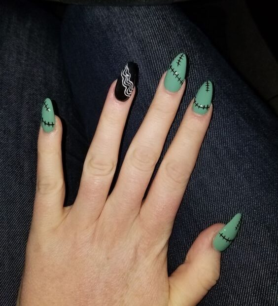 Vernis à ongles noir et vert sauge avec des tourbillons et des coutures nail art sur de longs ongles en amande