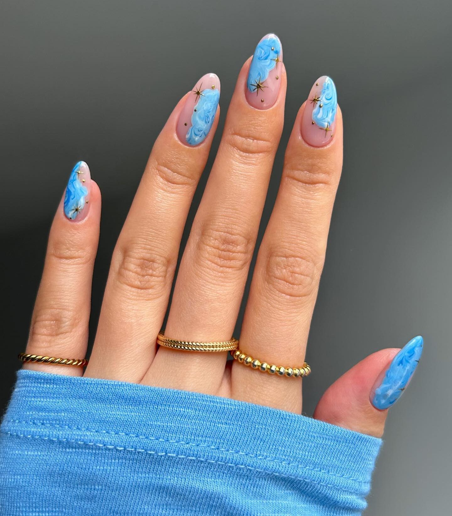 Conception d’ongles en marbre bleu clair avec des éléments célestes sur des ongles en acrylique de forme ronde moyenne