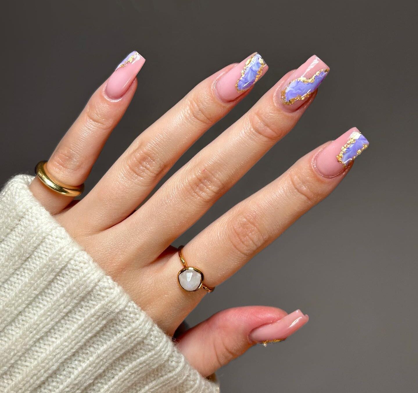 Vernis à ongles rose pâle avec motif d’ongles en marbre bleu électrique et doré sur de longs ongles carrés