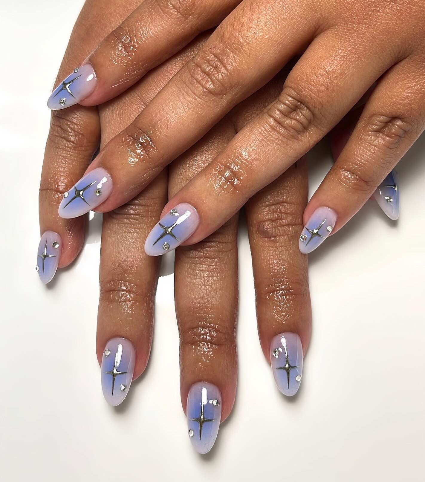 Effet dégradé d’aura bleu électrique avec des éléments célestes métalliques nail arts sur de longs ongles ronds en acrylique