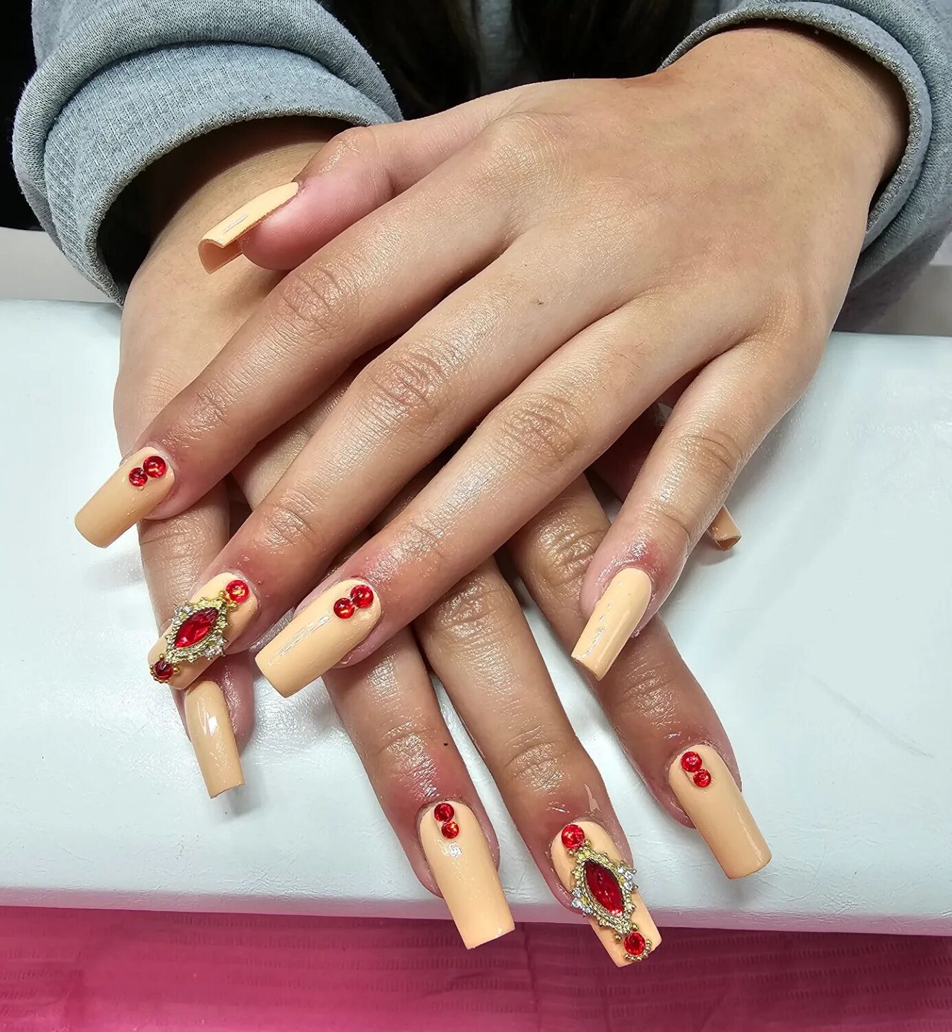 Couleur d’ongle jaune pâle avec des pierres précieuses rouges et des strass sur de longs ongles carrés