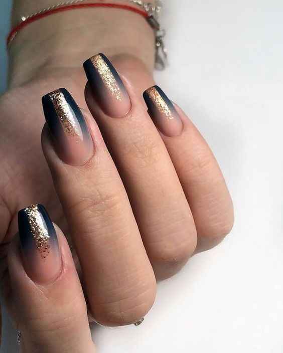 Ombre foncée avec des paillettes dorées en finition brillante sur des ongles de cercueil moyens