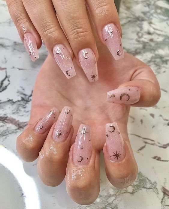 Ongles en acrylique en forme de cercueil longs avec des éléments célestes dorés nail arts