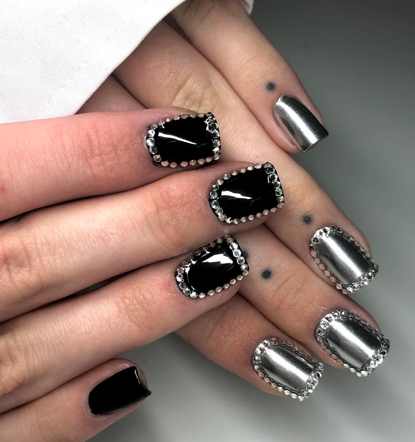 Couleurs d’ongles noir brillant et argent chromé avec strass sur ongles carrés courts