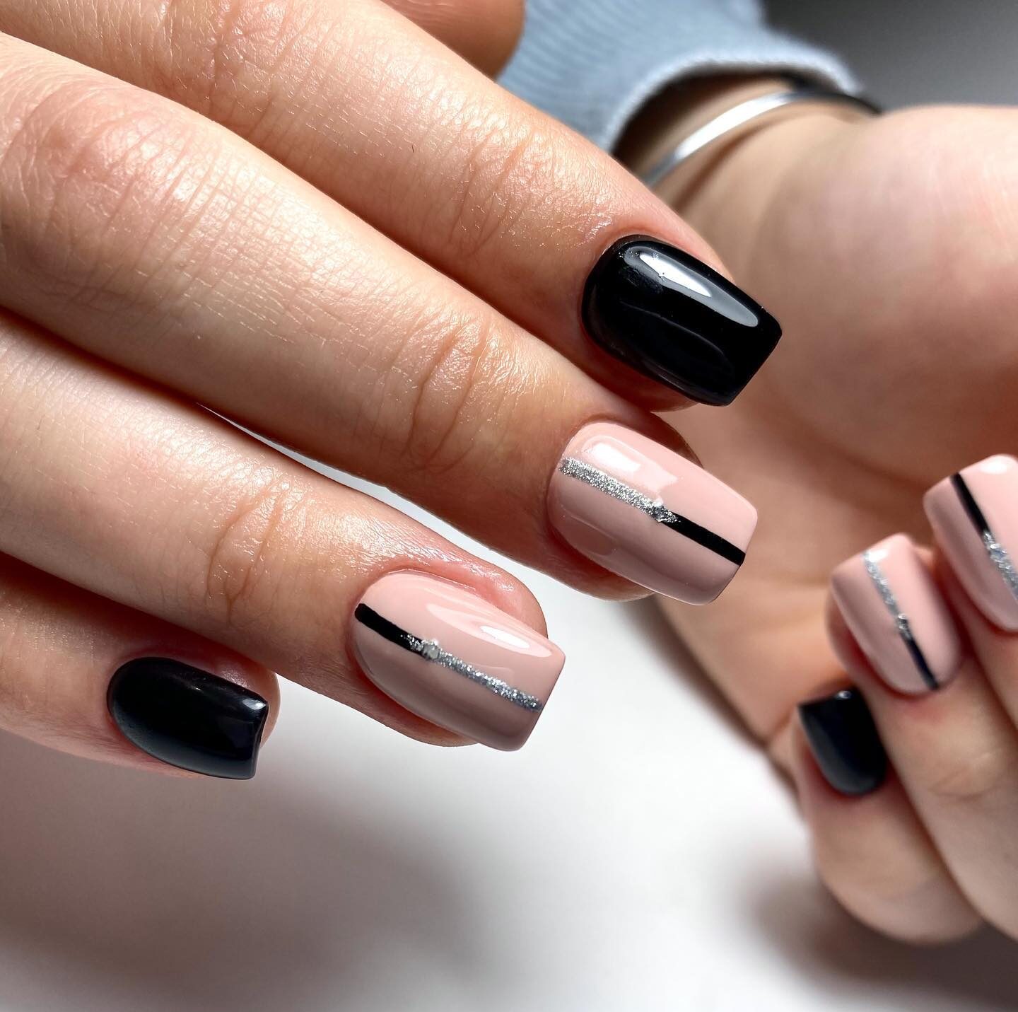 Couleurs d’ongles noires et nude avec un nail art chic sur des ongles carrés courts et effilés