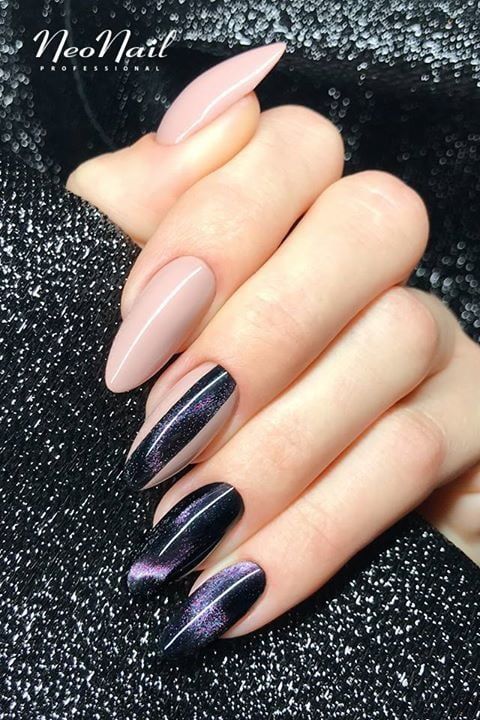 Couleur d’ongle nude avec un nail art noir et violet semblable à une galaxie sur de longs ongles en amande