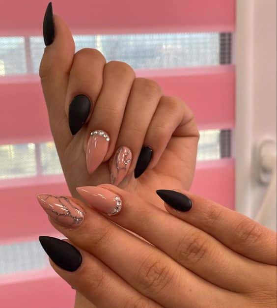 Couleurs d’ongles nude et noires avec strass et accents argentés sur les ongles aiguilles moyens