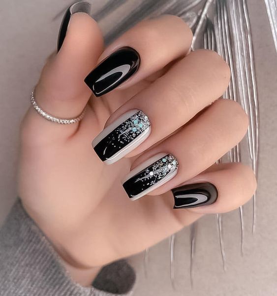 Couleur des ongles noire au fini brillant avec des paillettes argentées sur les ongles carrés moyens