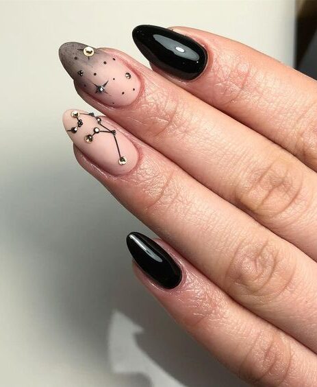 Vernis à ongles noir brillant et nude mat avec des nail arts célestes et constellations sur ongles en amande moyenne