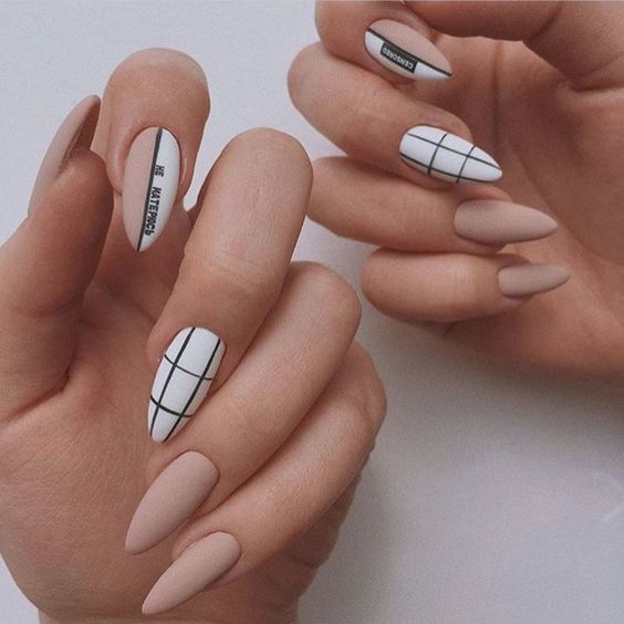 Couleur d’ongle nude au fini mat avec un design d’ongle noir et blanc tendance sur les ongles longs en amande