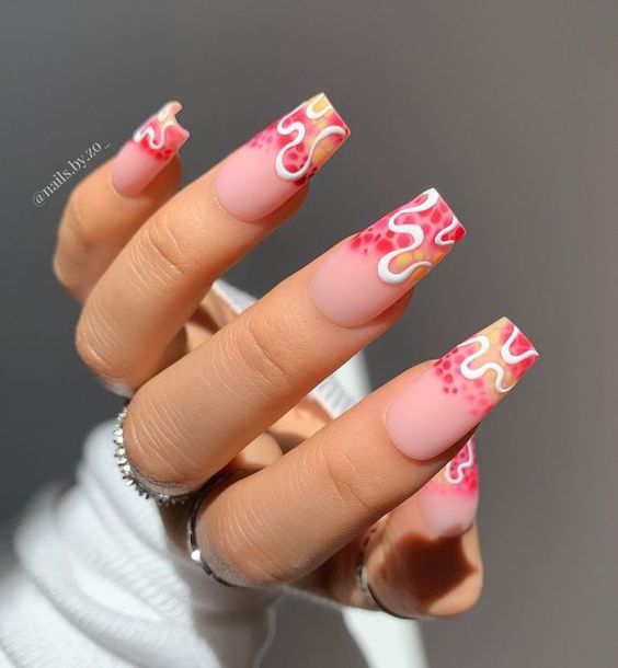 Ongles en acrylique de forme carrée effilée au fini mat long avec des points mouchetés roses et des motifs d’ongles tourbillons blancs