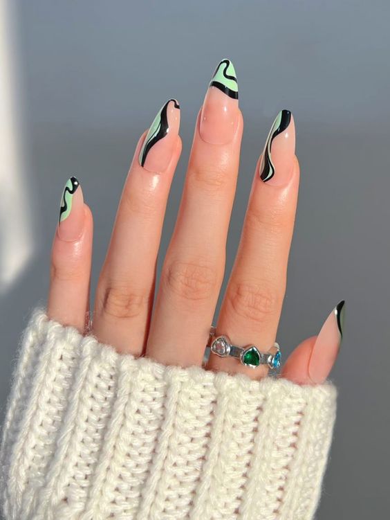 Tourbillons verts et noirs sur les ongles en amande