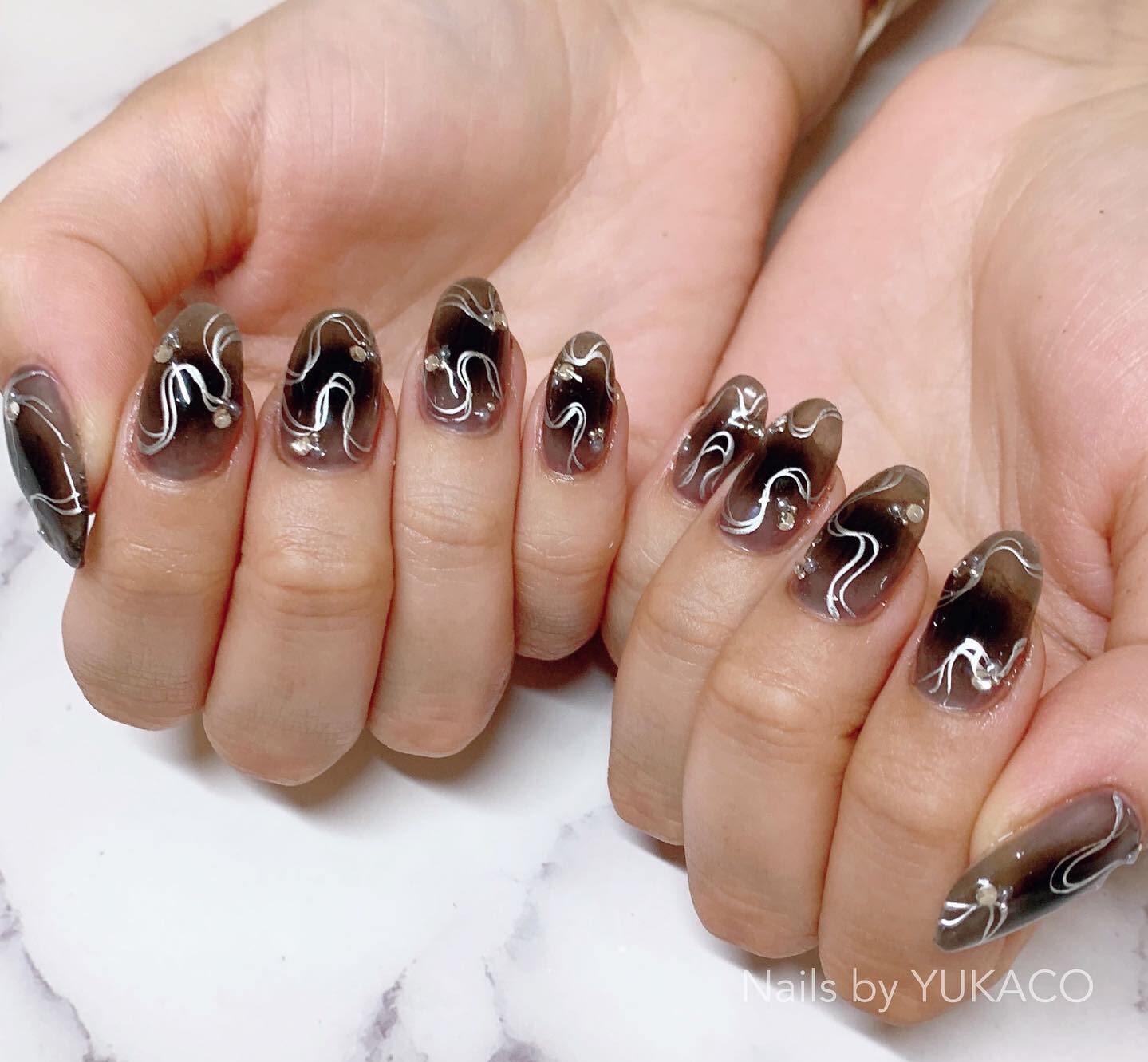 Nail art ombré noir avec des tourbillons argentés sur des ongles ronds moyens