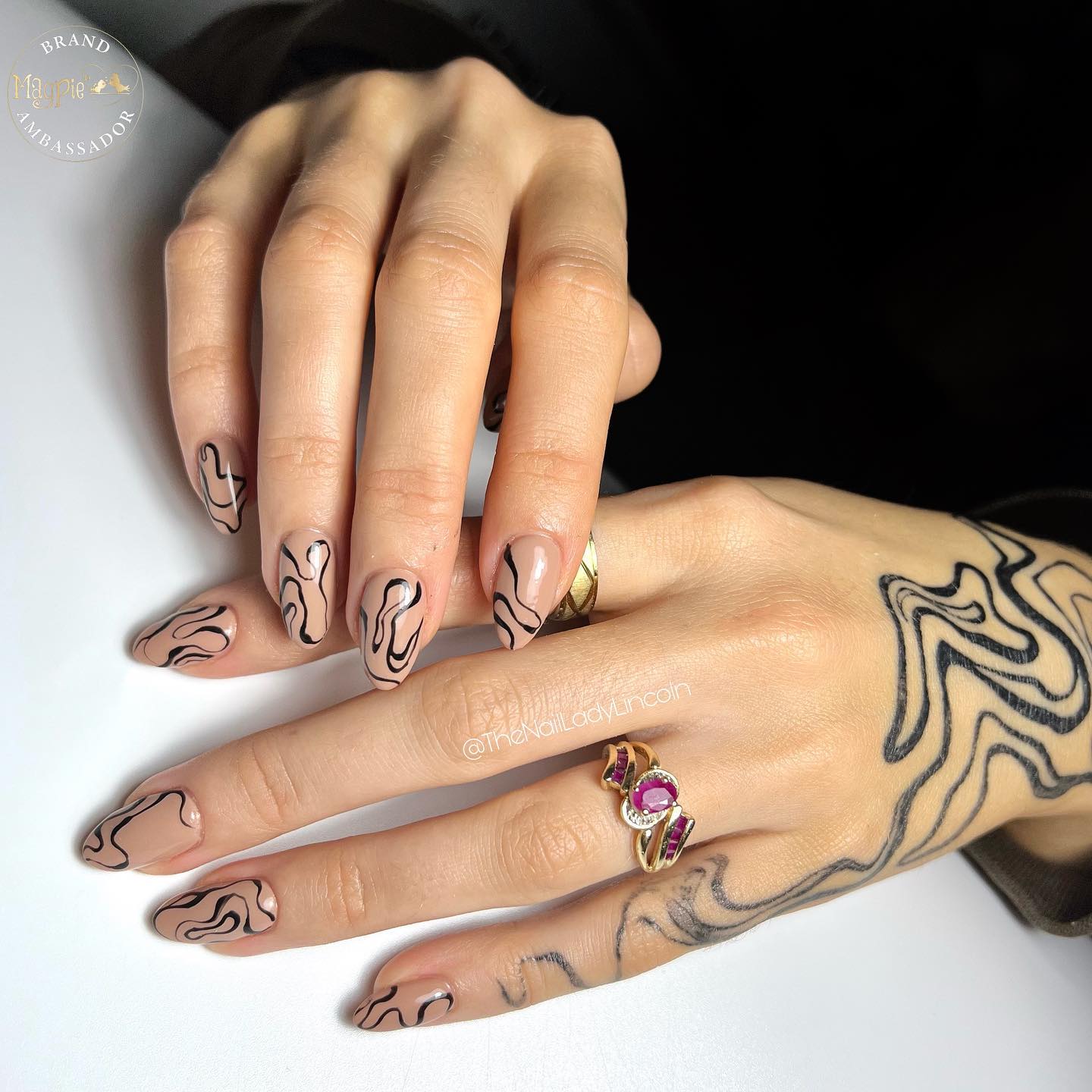 Vernis à ongles nude avec des tourbillons noirs complexes sur des ongles en amande moyens