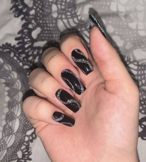 Couleur d’ongle noire avec des tourbillons argentés nail art sur de longs ongles carrés