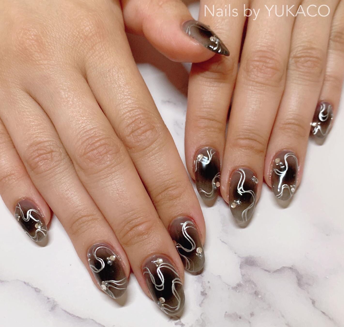 Nail art ombré noir avec des tourbillons argentés sur des ongles ronds moyens