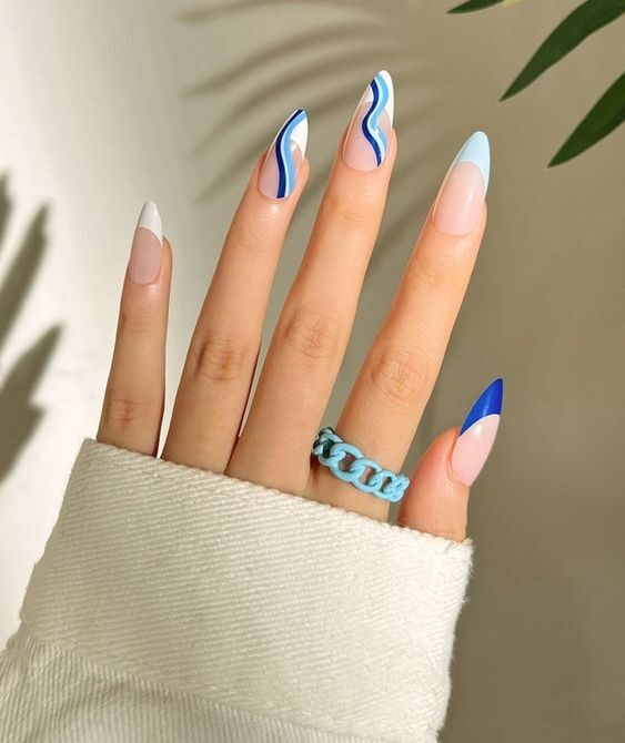 Ongles longs en acrylique clairs en forme d’amande avec pointes et tourbillons français blancs et bleus