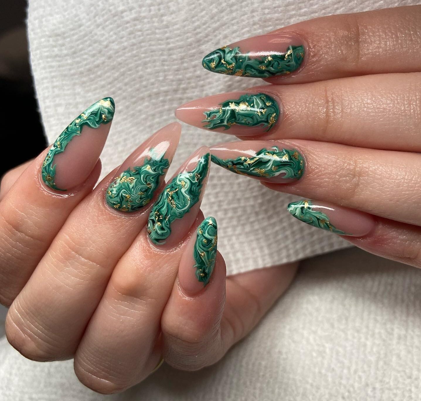 Nail art en marbre vert avec des accents de feuille d’or sur de longs ongles en acrylique en forme d’amande