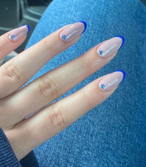 Couleur bleue, pointes françaises fines et nail art mauvais œil sur ongles ronds moyens