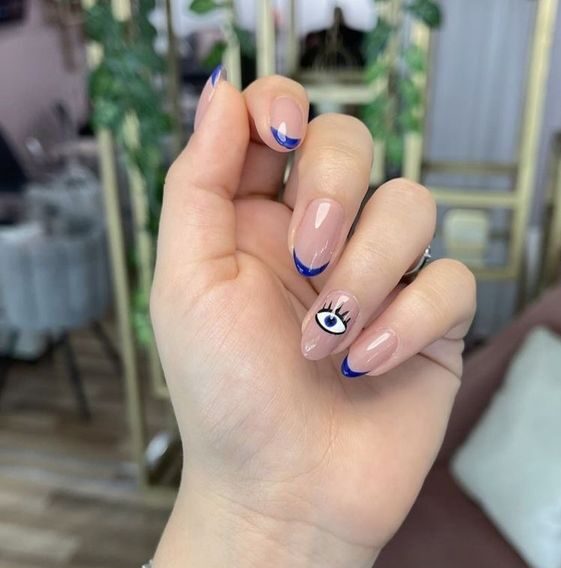 Couleur bleue, pointes fines à la française et nail art du mauvais œil sur ongles courts et ronds