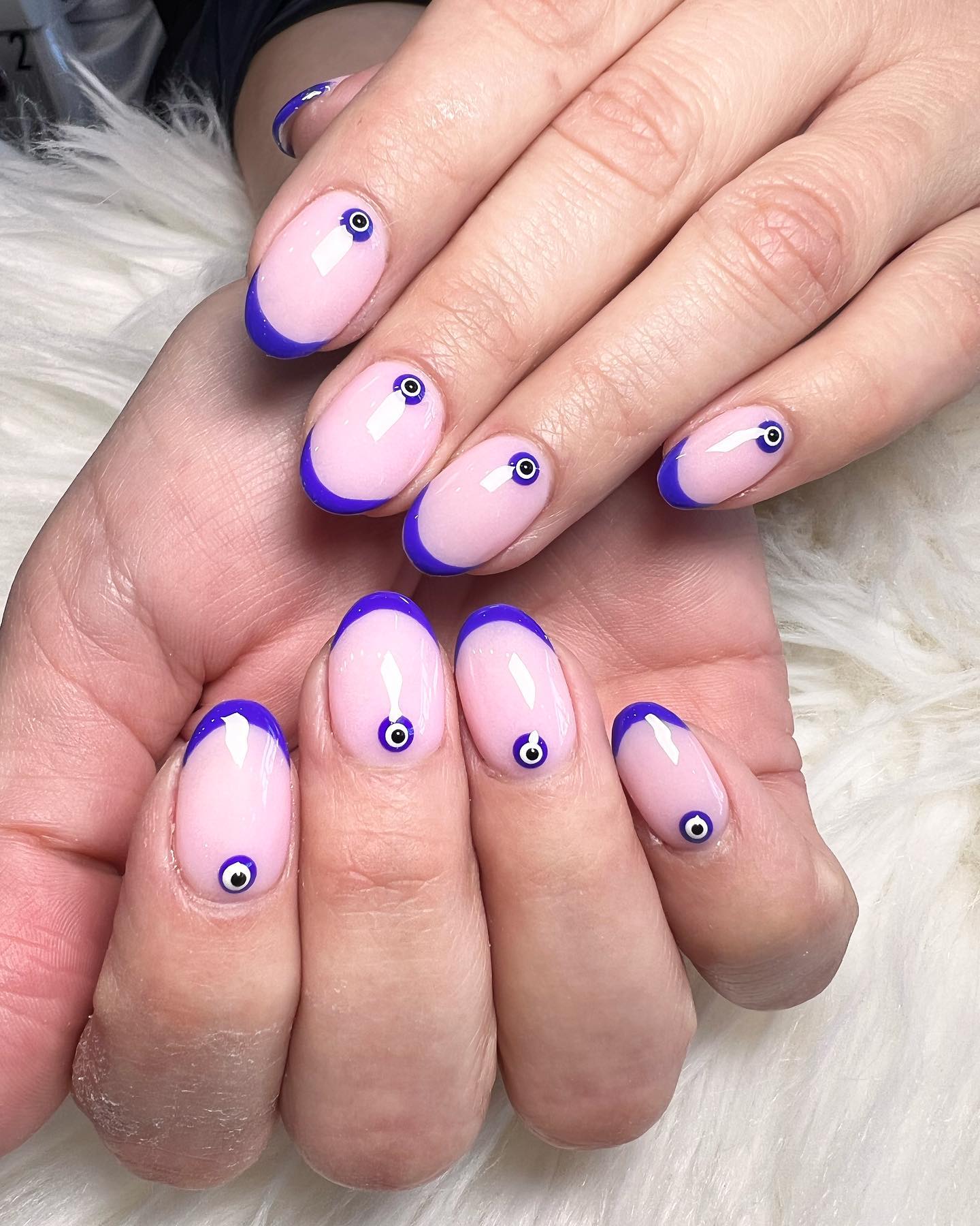 Couleur bleue, pointes fines à la française et nail art du mauvais œil sur ongles courts et ronds