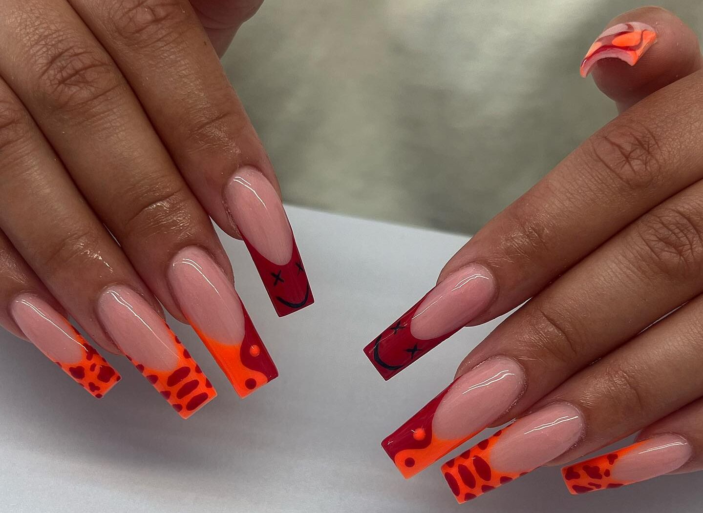 Pointes françaises rouges et oranges avec nail art abstrait sur des ongles carrés super longs