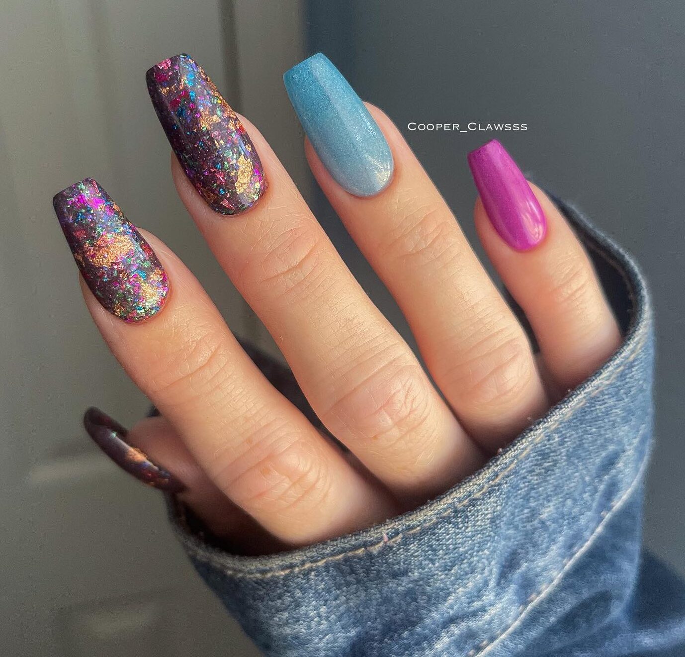 Couleurs d’ongles violet foncé et bleu électrique avec des paillettes sur de longs ongles de cercueil