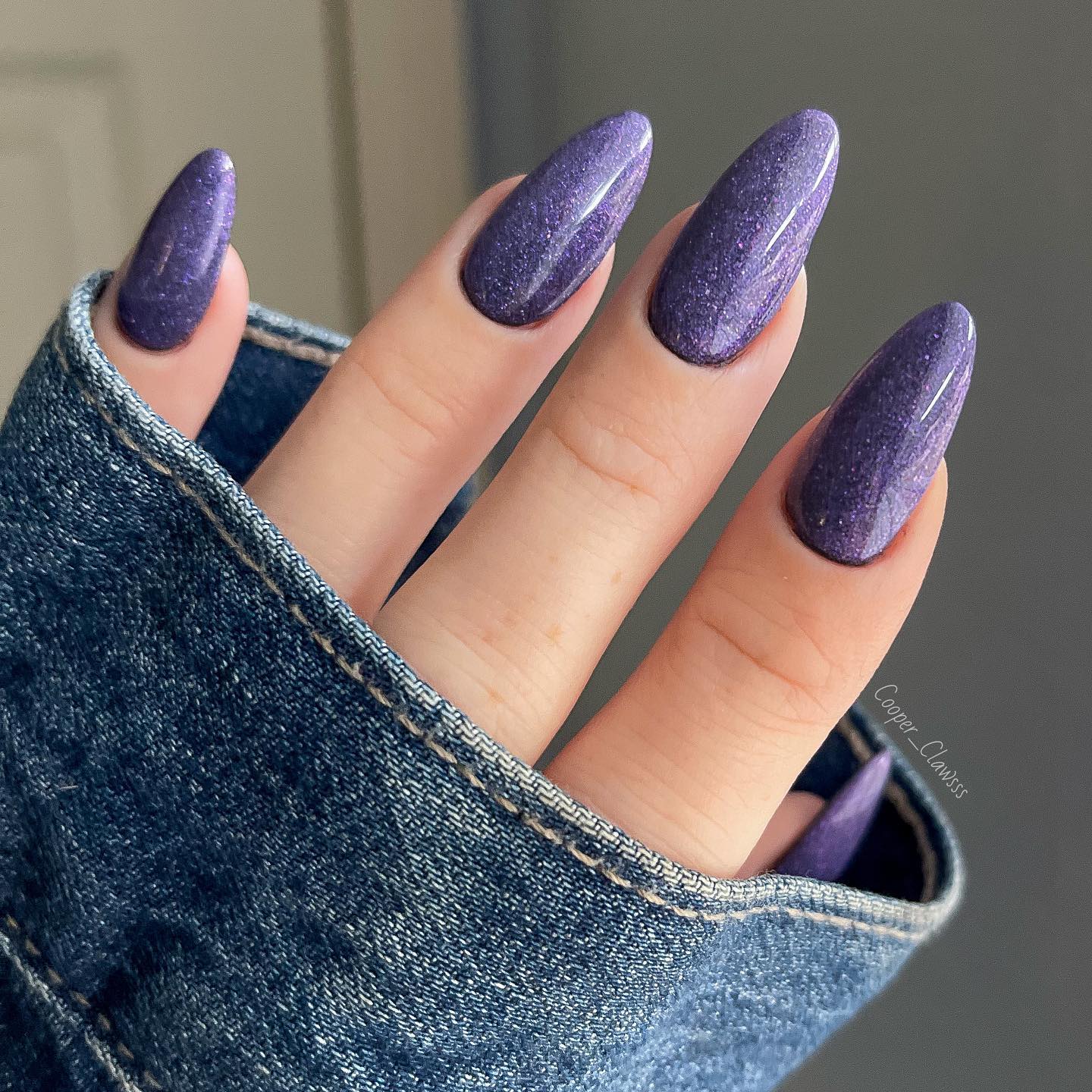 Vernis à ongles violet uni avec des paillettes sur les ongles longs en amande