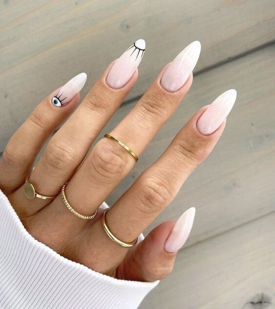 Couleur d’ongle blanc pâle avec conception d’ongles de mauvais œil sur les ongles longs en amande