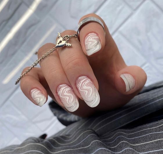 Motifs géométriques blancs sur de longs ongles ronds