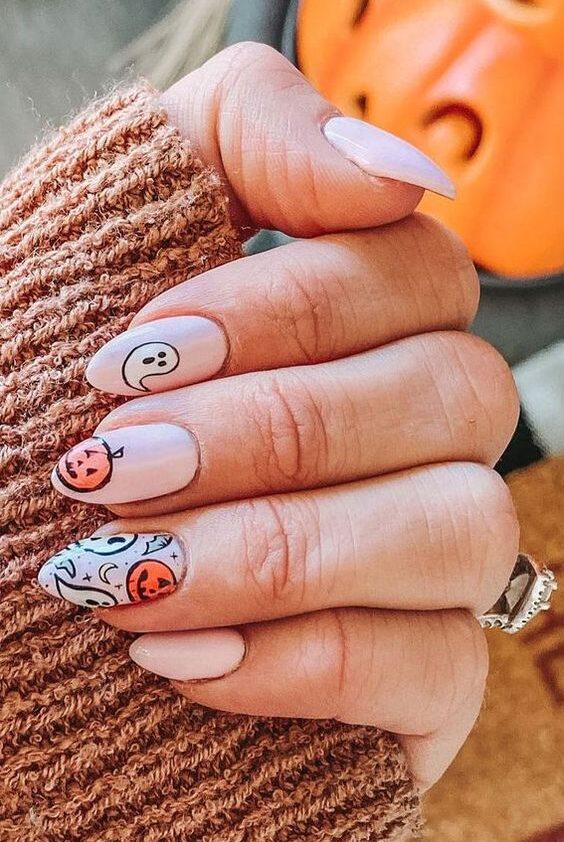 Vernis à ongles blanc pâle avec des fantômes et des arts d’ongles citrouille sur des ongles en amande moyens