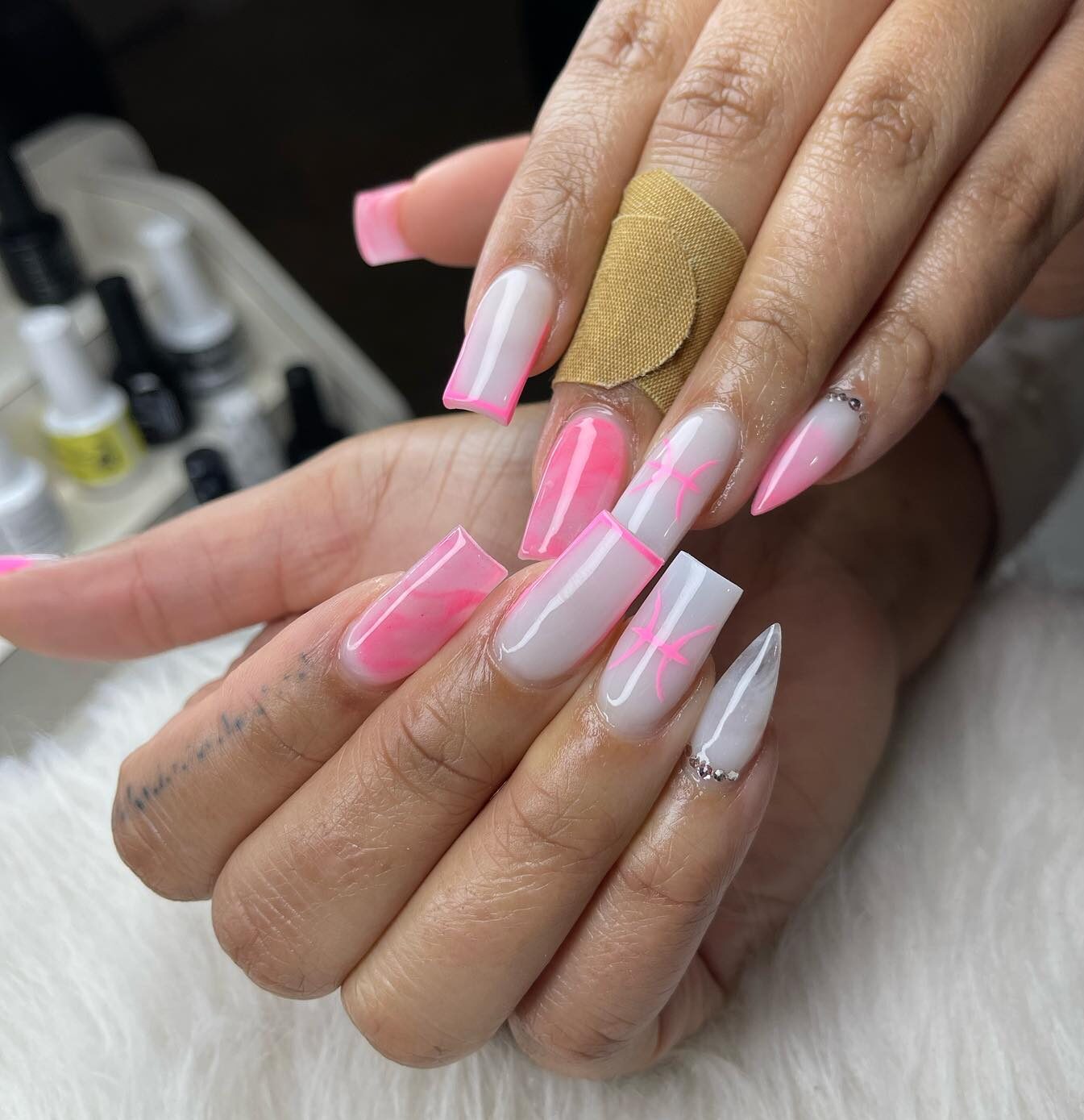 Ongles en acrylique de forme carrée blanc pâle avec du marbre rose, de fines pointes françaises et des nail arts du signe des Poissons