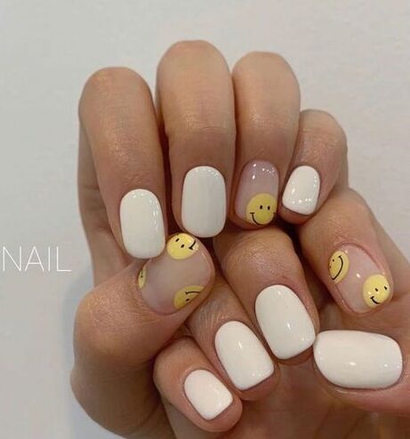 Vernis à ongles blanc et visages souriants jaunes nail art sur ongles courts