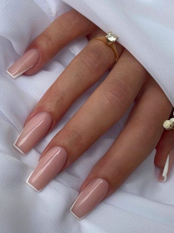 Couleur d’ongle nude avec de fines pointes françaises blanches sur des ongles longs et carrés