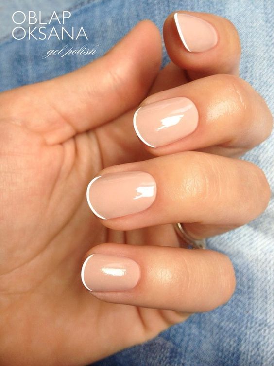 Vernis à ongles de couleur beige avec des pointes françaises fines blanches sur des ongles courts et ronds