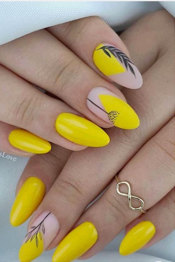 Vernis à ongles jaune avec des plantes sur les ongles en amande