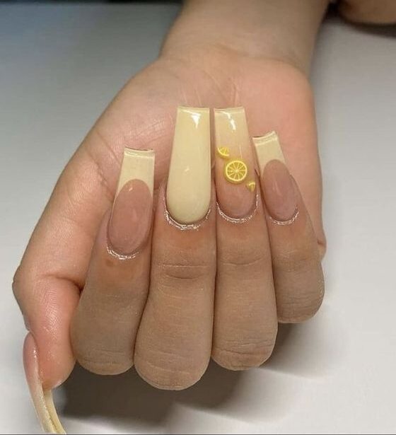 Couleur d’ongle jaune pâle, pointes françaises et nail art citron sur de longs ongles carrés effilés en acrylique