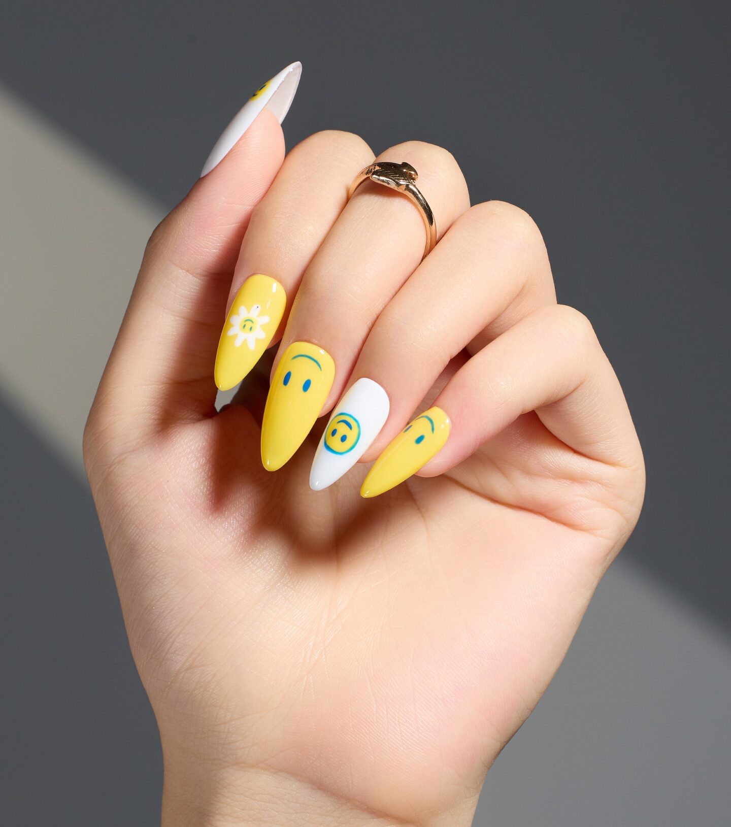 Couleur d’ongle jaune et blanc avec smiley jaune nail art sur de longs ongles en amande