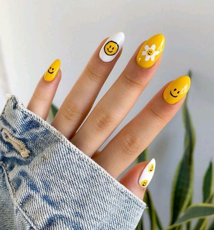 Couleur d’ongle jaune et blanc avec des visages souriants jaunes nail art sur ongles amandes moyens