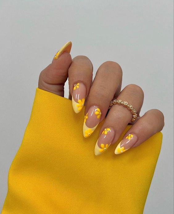 Pointes jaunes françaises avec des fleurs jaunes sur des ongles en amande